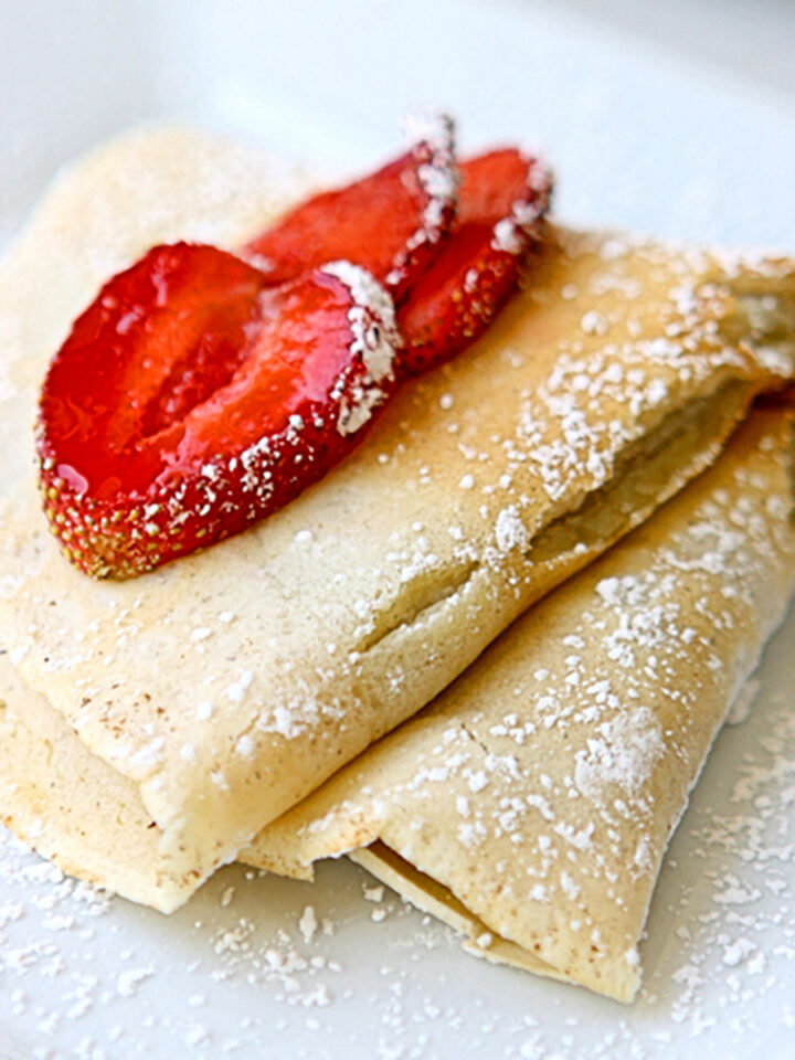 Folded crepe with sliced strawberries on a white plate