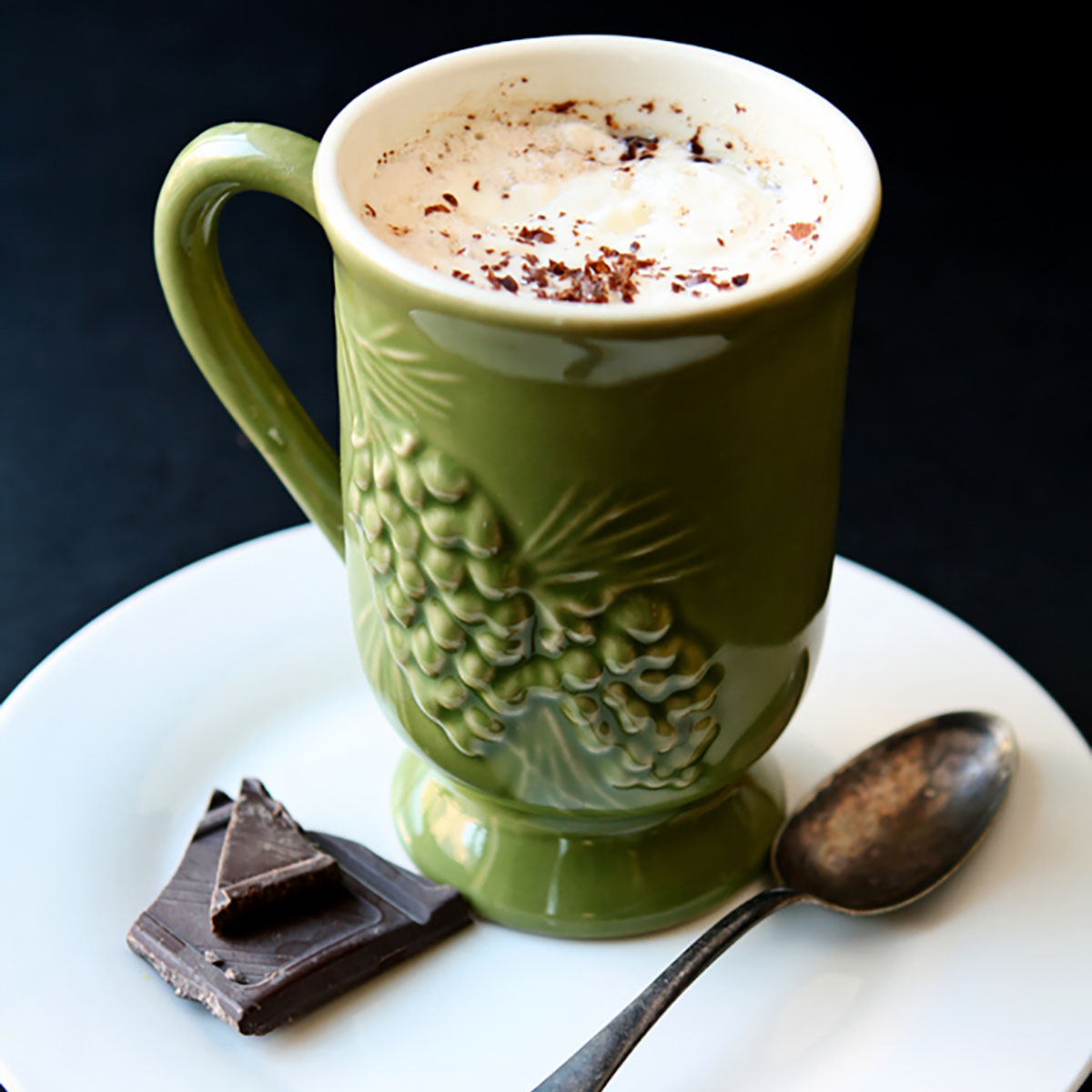 Almond roca mocha in a green mug on a white plate