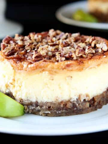 Small apple pecan cheesecake topped with chopped pecans on a white plate