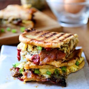 Breakfast Panini | Take your breakfast to the next level! Sun-Dried tomato pita bread, pesto, three kinds of cheese, scrambled eggs, bacon, sausage, roasted red peppers and scallions. A delicious and hearty breakfast sandwich that will keep you going all day. Ready in less than 30 minutes!| heavenlyhomecooking.com