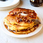 Cornbread pancakes with butter pecan syrup on a white plate