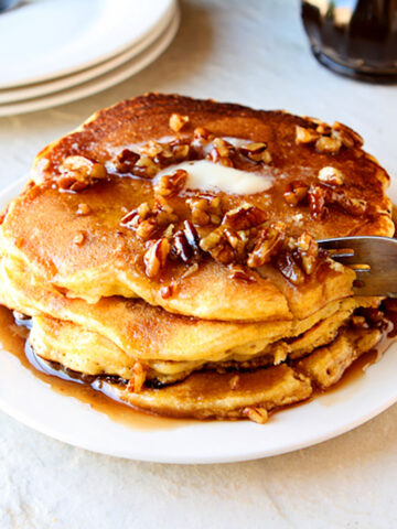 Cornbread pancakes with butter pecan syrup on a white plate