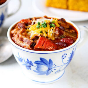 Three-bean chili in a blue floral mug on a marble background.