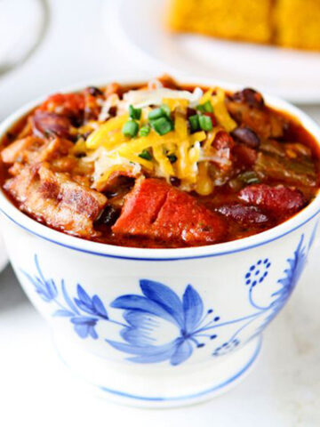 Three-bean chili in a blue floral mug on a marble background.