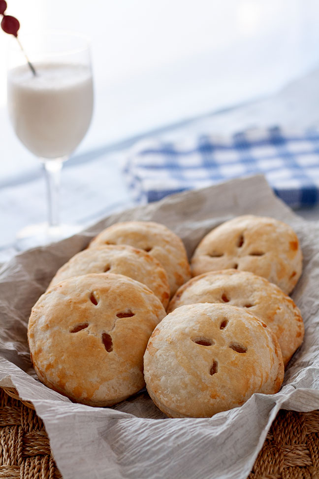 Six mini pies sitting in a paper-lined basket.