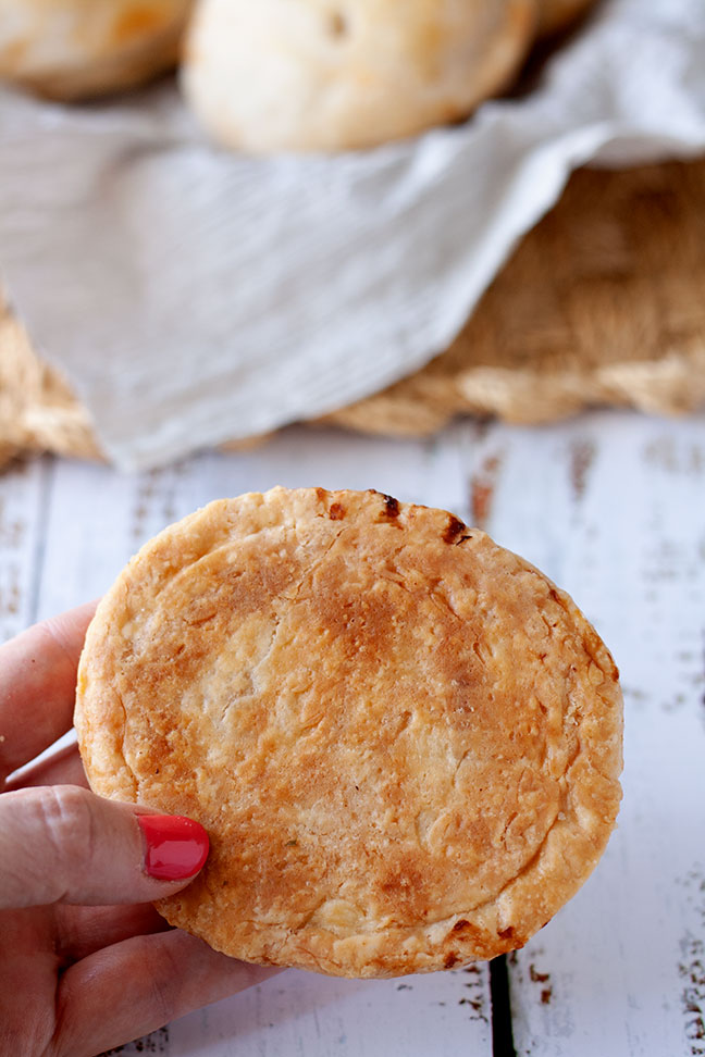 A hand showing the underside of a baked mini pie.