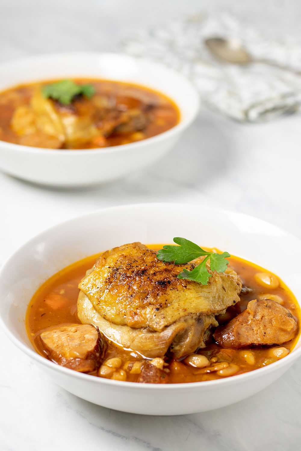 Chicken and sausage stew in two white bowls