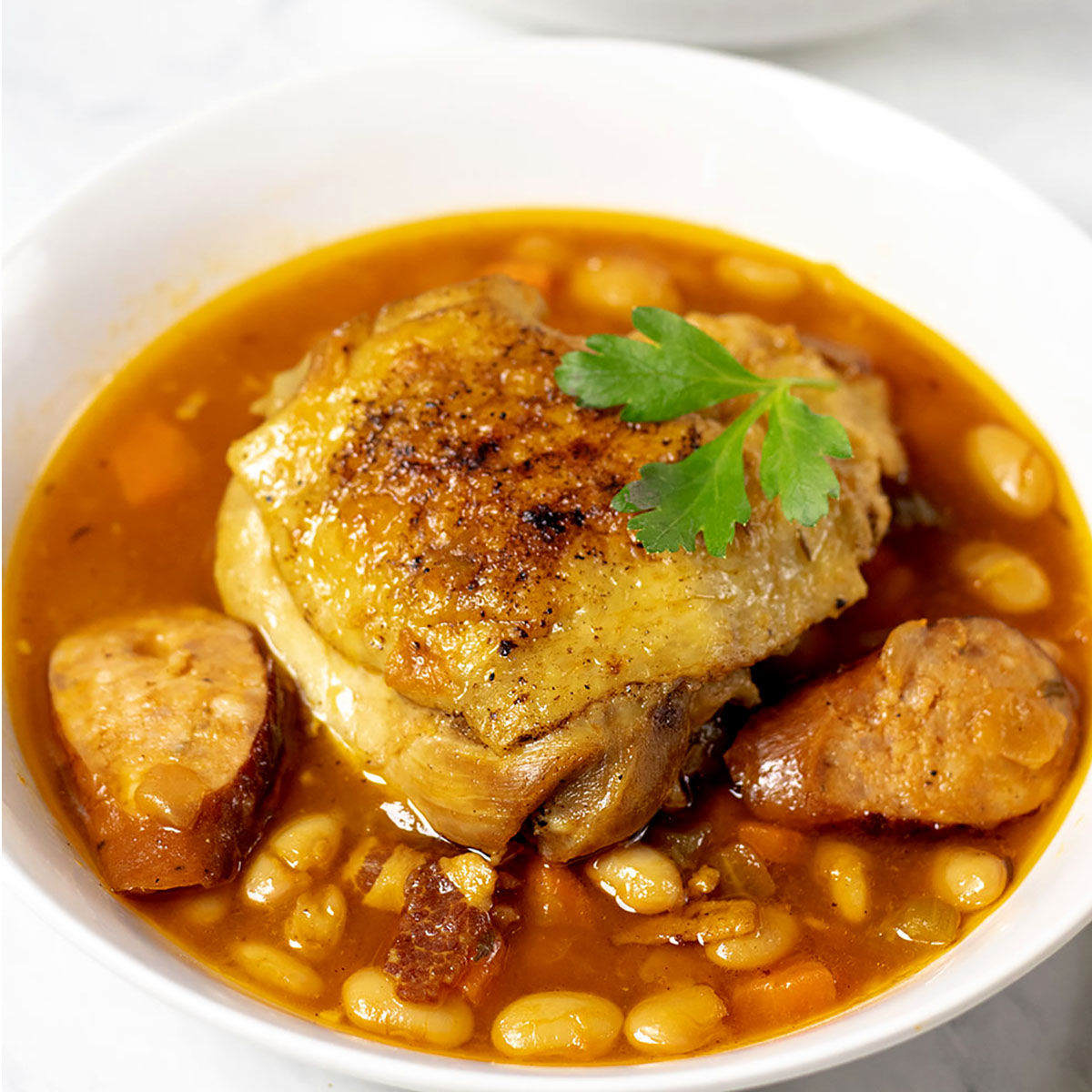 Close up of chicken and sausage stew in a white bowl