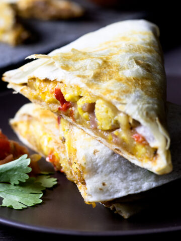 Close up of stacked breakfast quesadilla on a brown plate