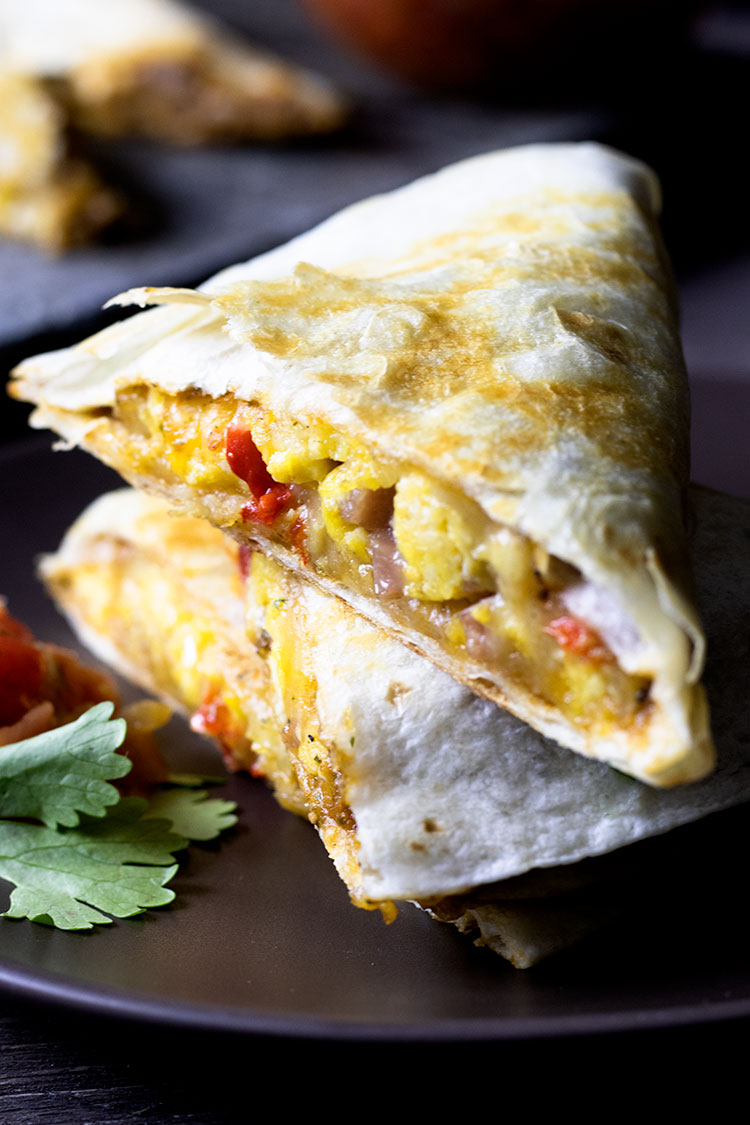 Close up of stacked breakfast quesadilla on a brown plate