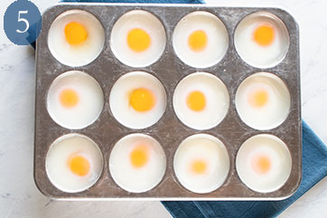 Twelve well muffin tin with each well containing one poached egg.