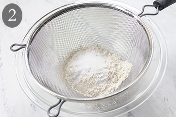 Dry ingredients in a sifter over a bowl.