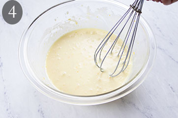 Bubbling wet ingredients in a bowl with a whisk.
