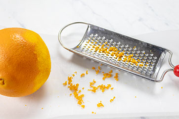 Orange, zest and cheese grater on a table