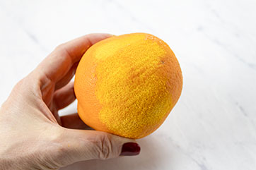 Hand holding a partially-zested orange