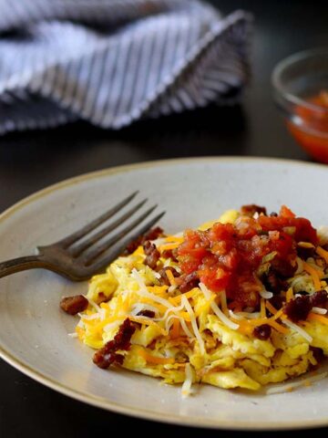Cheesy scrambled eggs sitting on white plate.