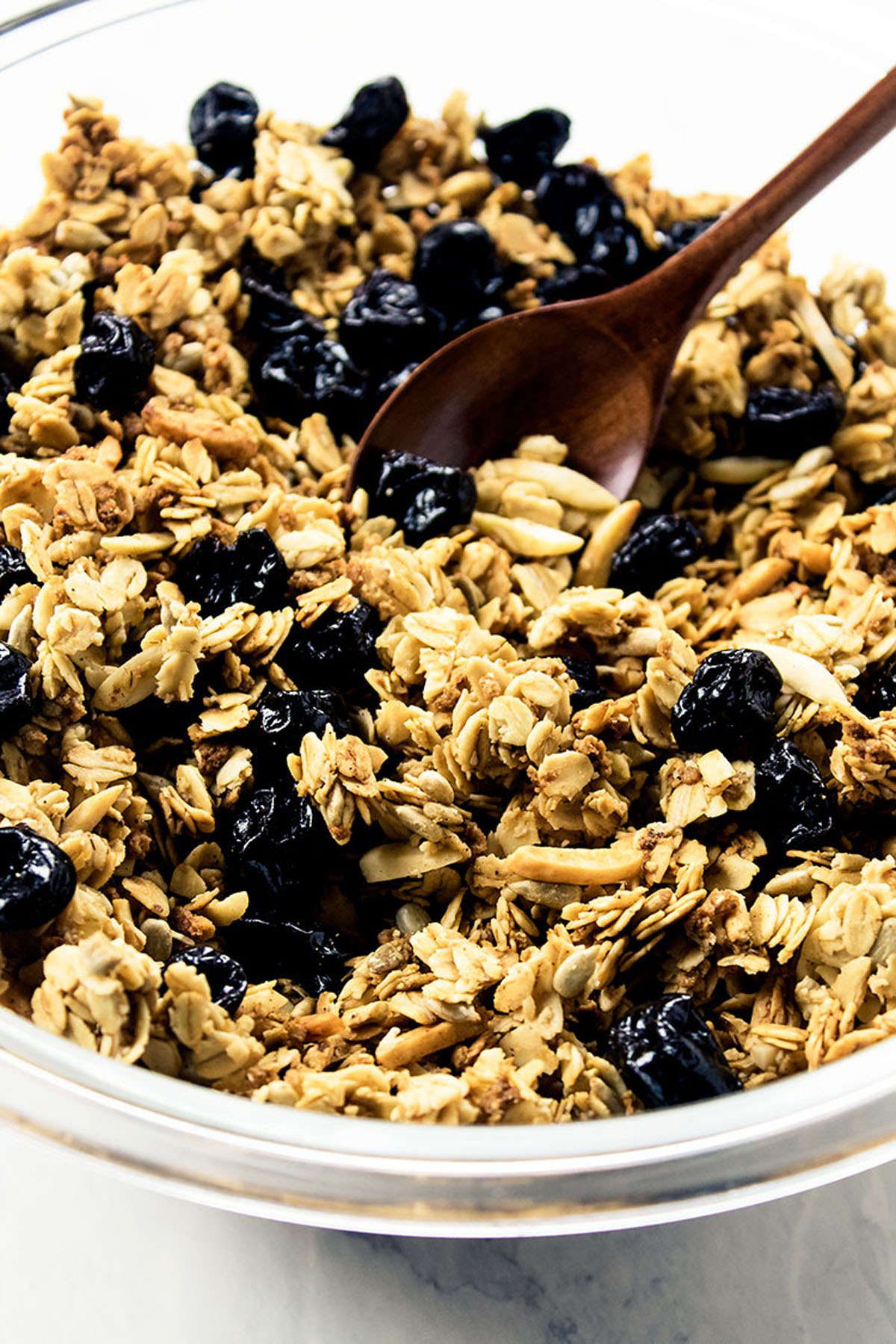 Close up of granola and wooden spoon in a glass bowl