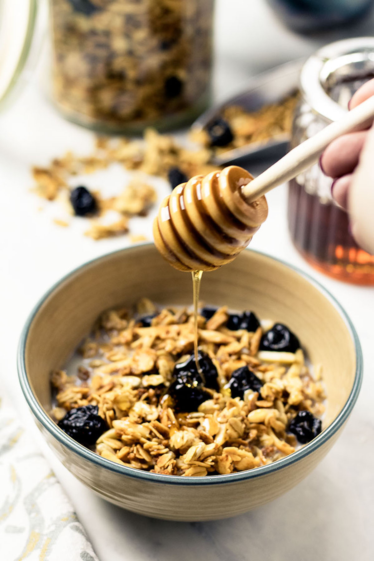 Honey being drizzled over a bowl of granola in milk