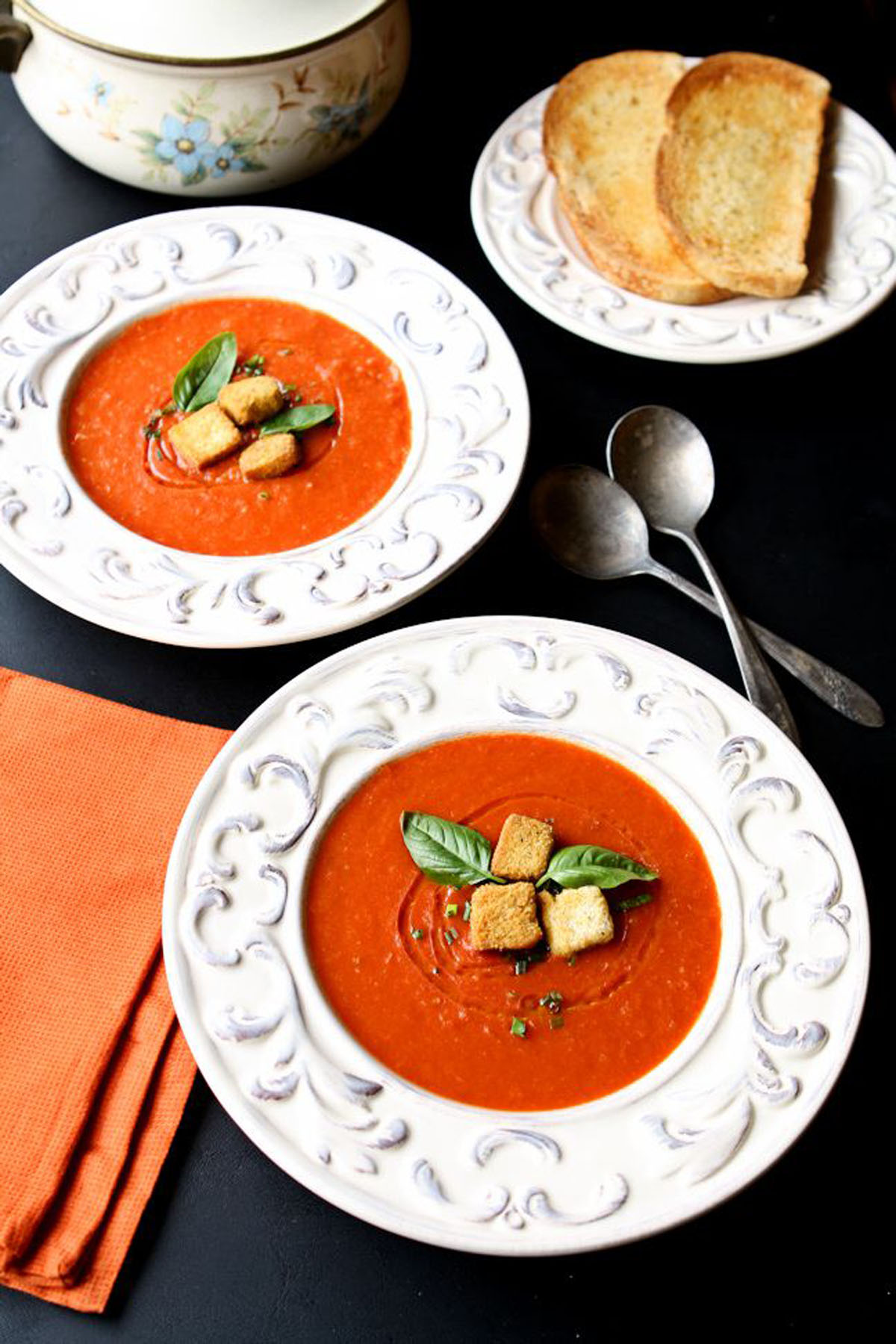 Tomato soup in two white bowls on a black table.