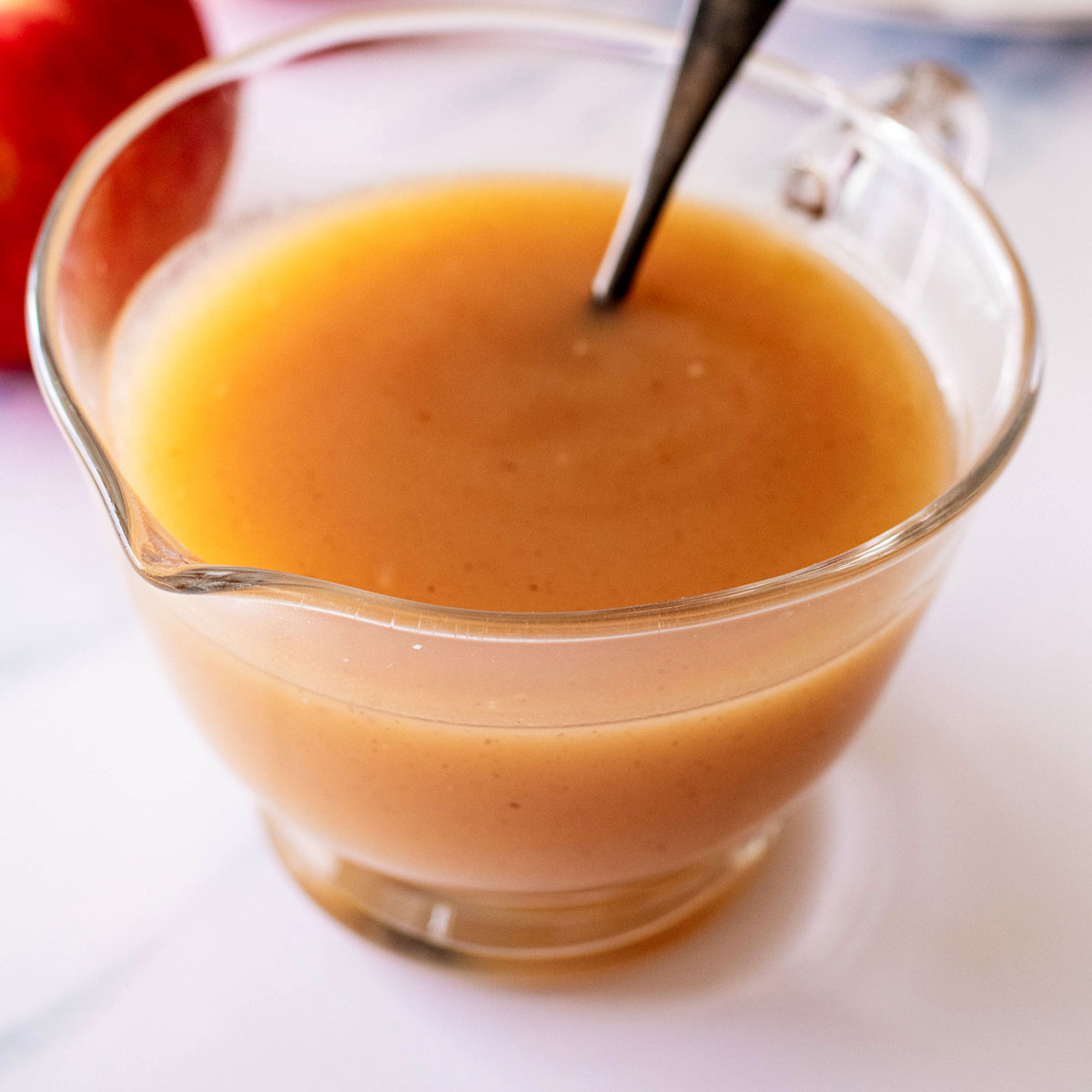 Apple syrup in a glass pitcher with spoon