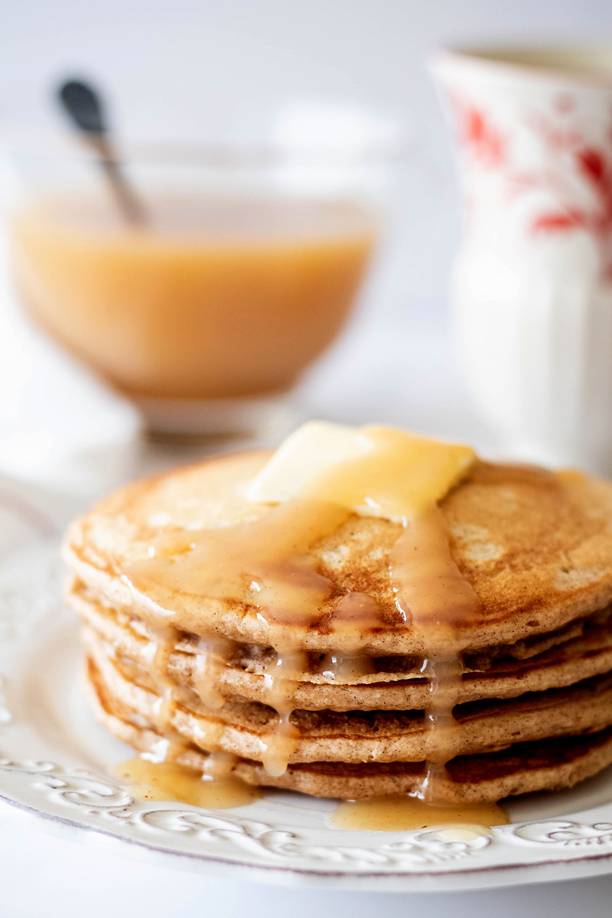 Stack of cinnamon oatmeal pancakes with a pat of butter and syrup on a white plate