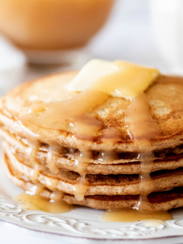 Stack of cinnamon oatmeal pancakes on a white plate