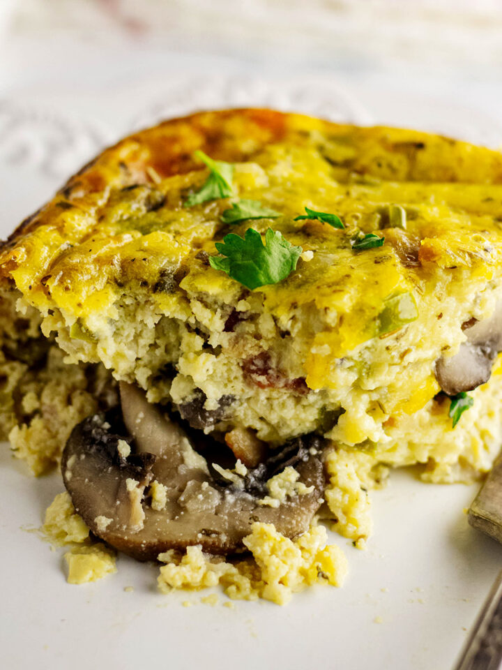 Slice of mushroom breakfast casserole on a white plate with fork