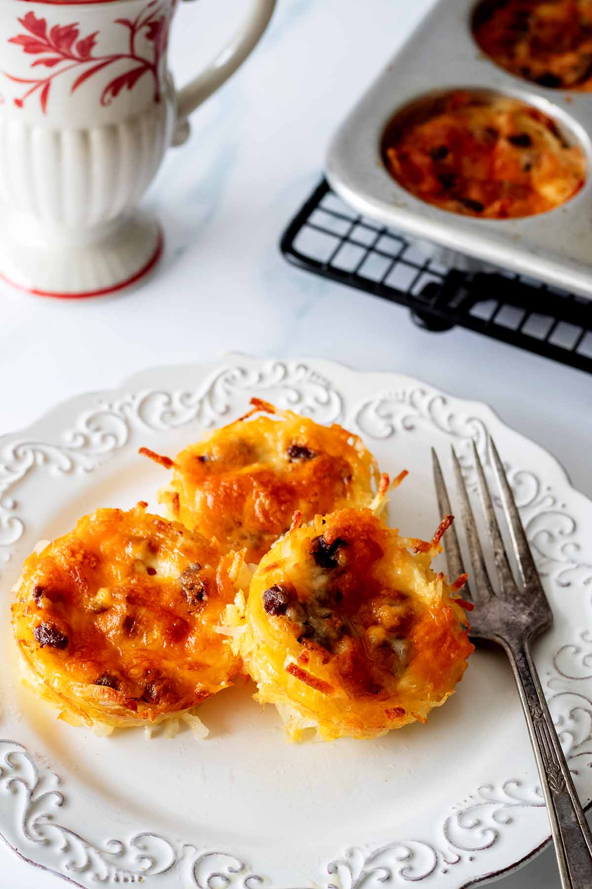 Breakfast hash brown egg muffins on a white plate with a fork