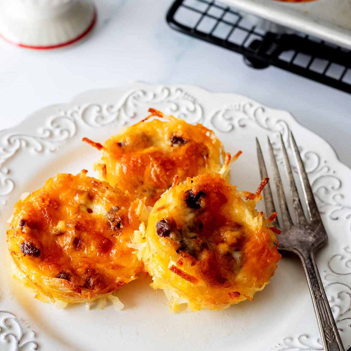 Hash brown egg muffins on a white plate with a fork