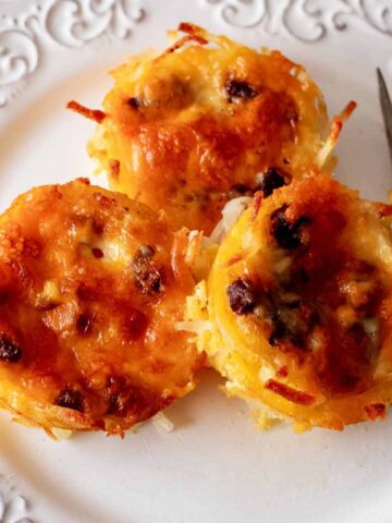 Overhead view of hash brown egg muffins on a white plate with a fork