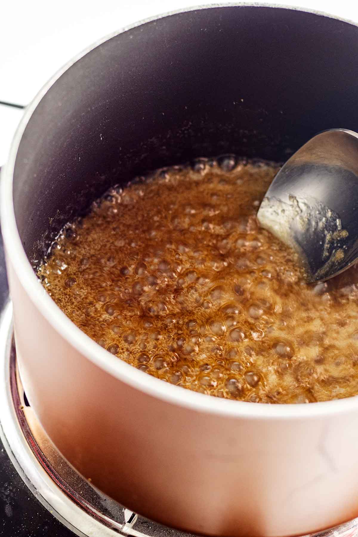 Caramel syrup cooking in a saucepan with spoon