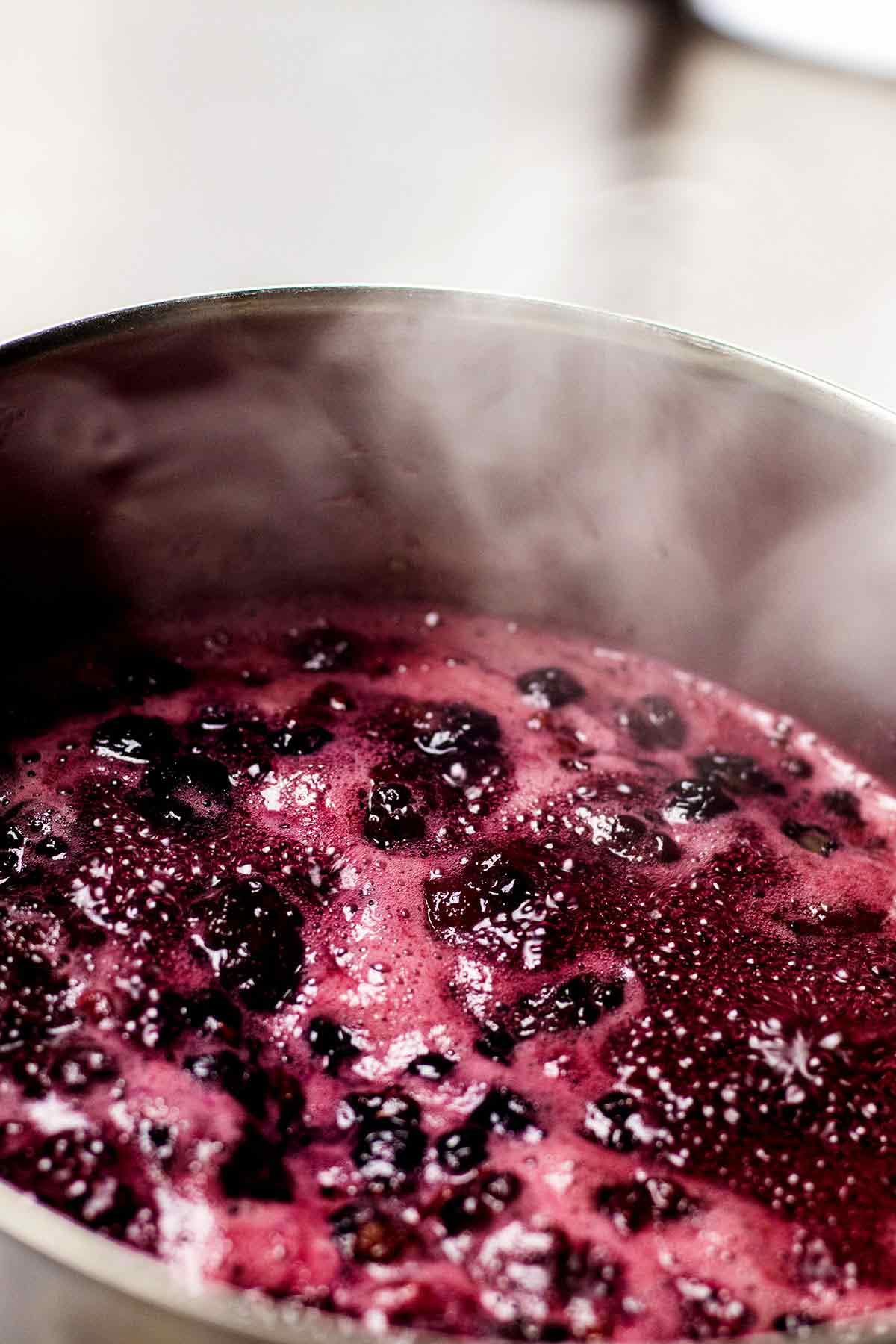 Berry syrup cooking in a saucepan.