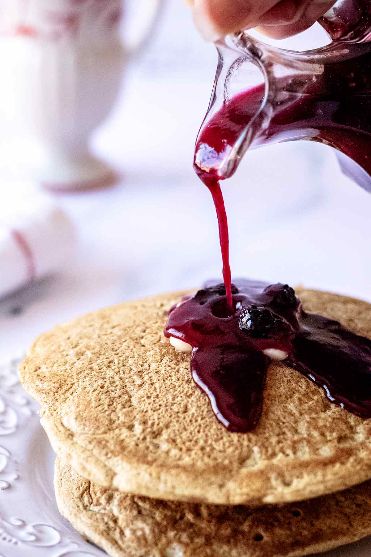 Syrup being poured over pancakes