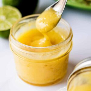 Fresh lime curd in a glass jar with a spoon