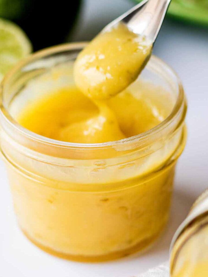 Fresh lime curd in a glass jar with a spoon