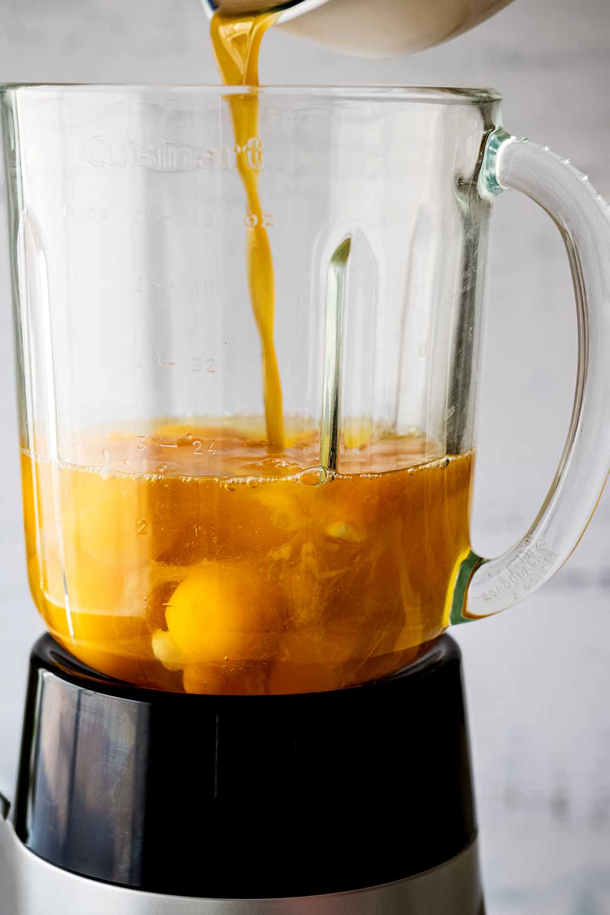 Raw eggs in a blender. Liquid from green chiles is being poured over the top.