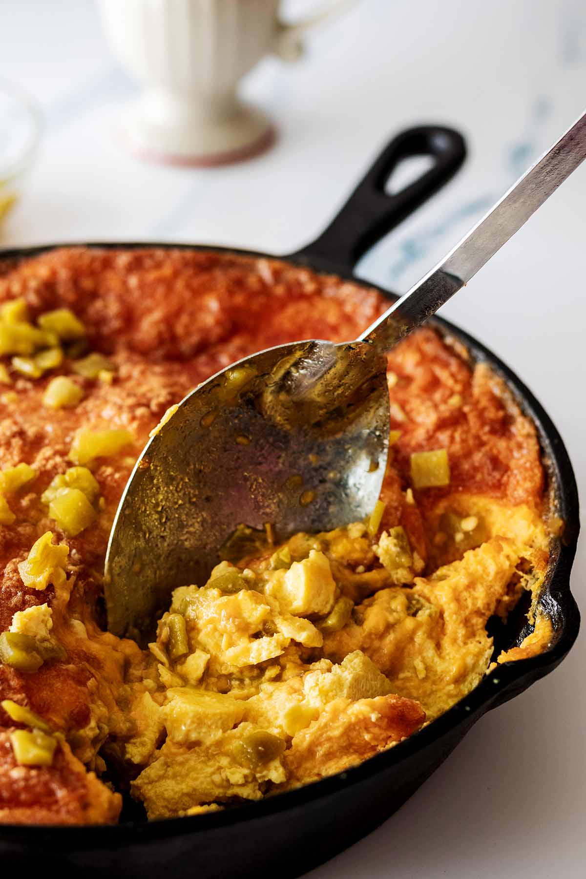 Serving spoon scooping out a serving of baked green chile breakfast casserole