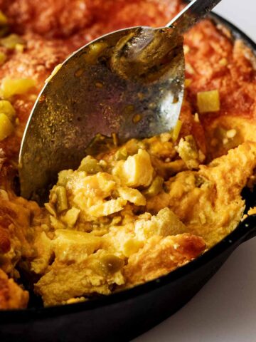 Serving spoon scooping out a serving of baked green chile breakfast casserole