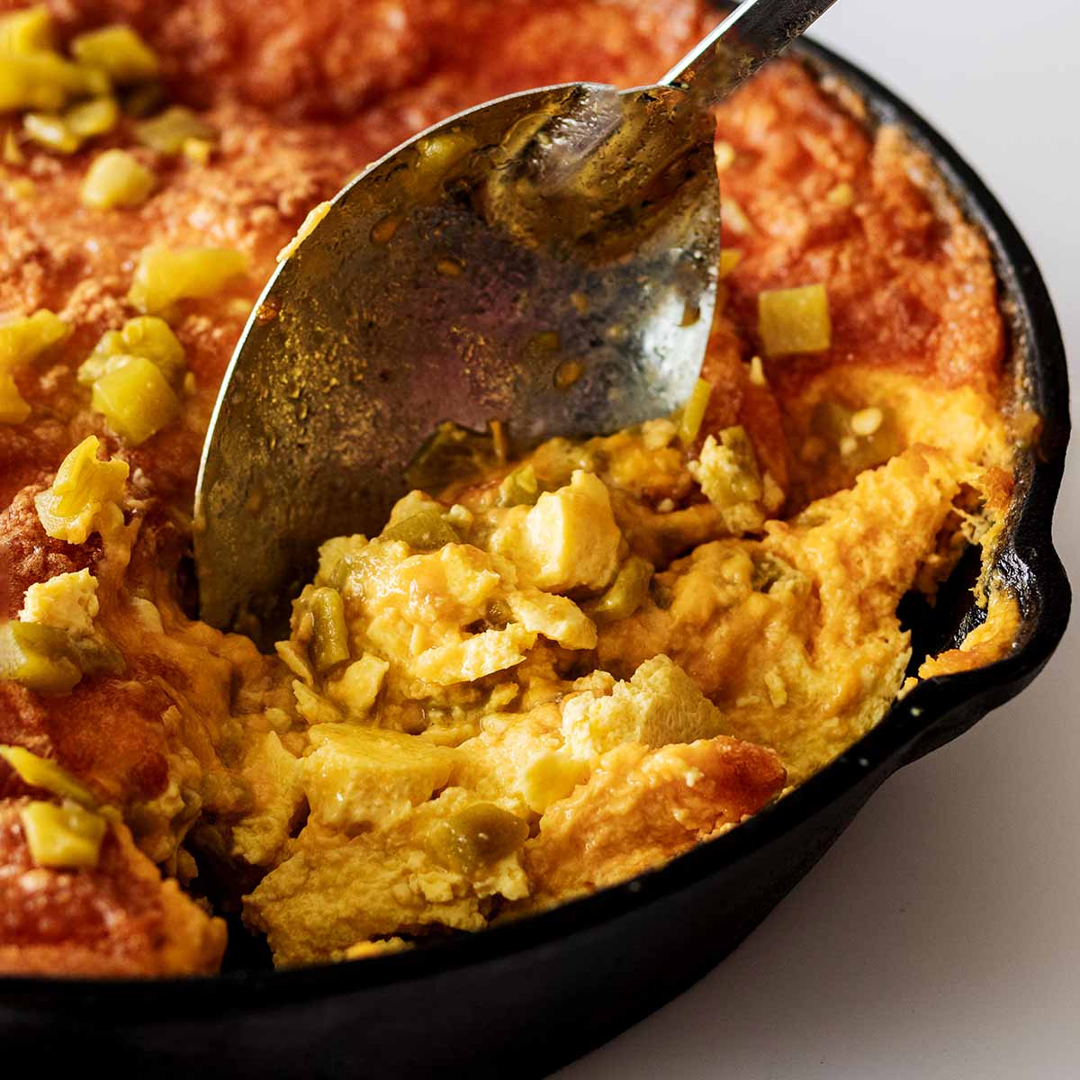 Serving spoon scooping out a serving of baked green chile breakfast casserole