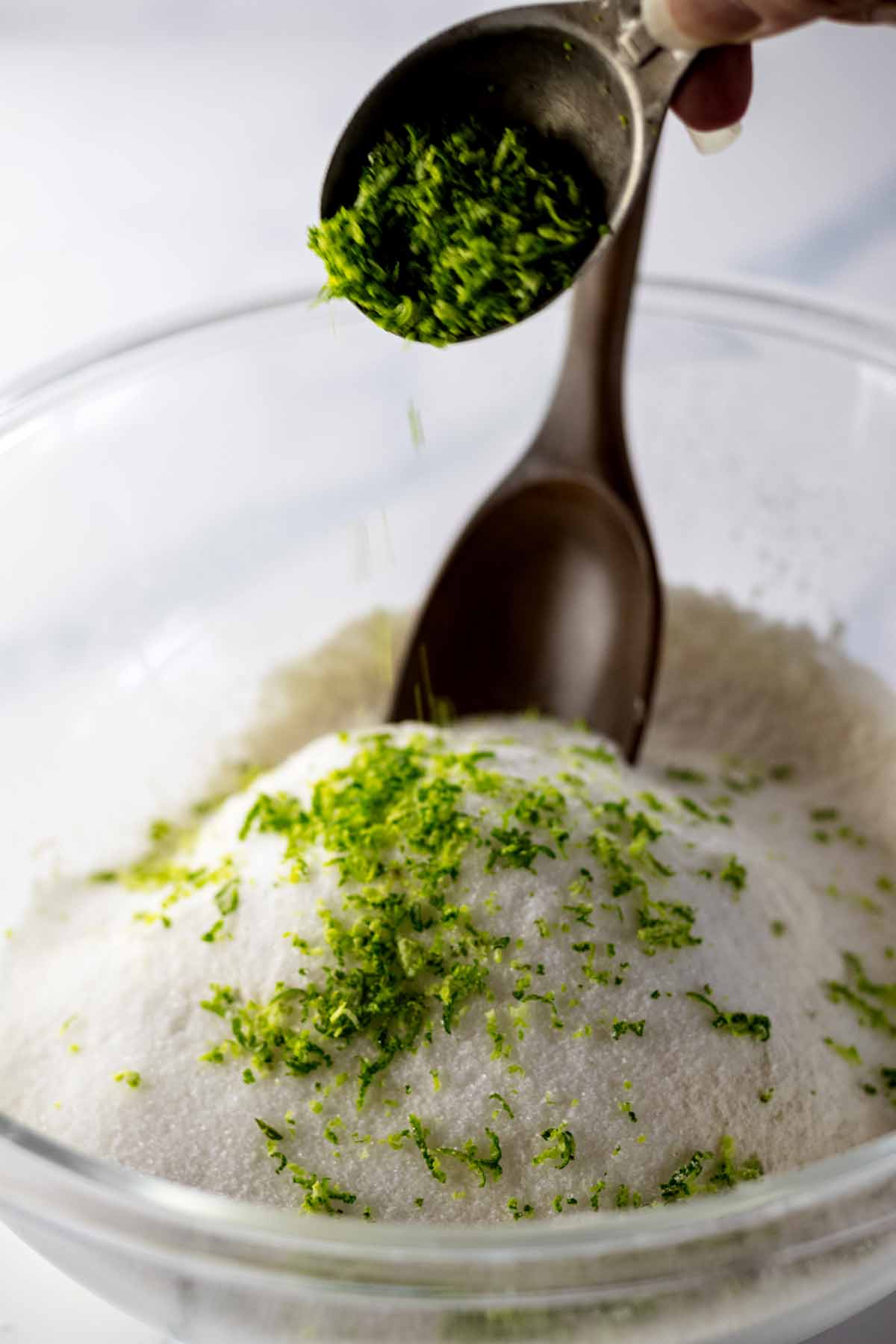 Spooning lime zest over dry ingredients