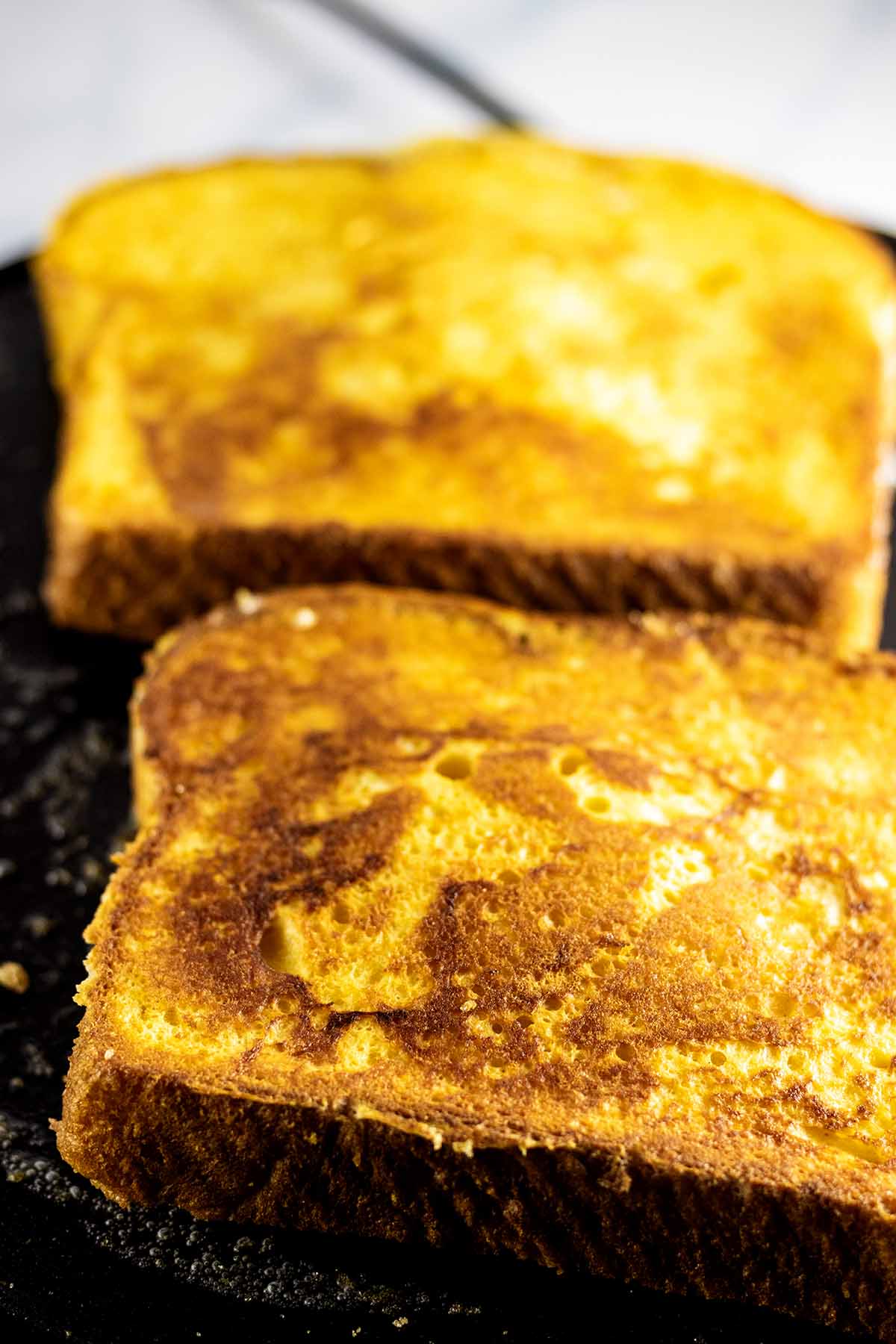 Two slices of golden brown bread on a griddle