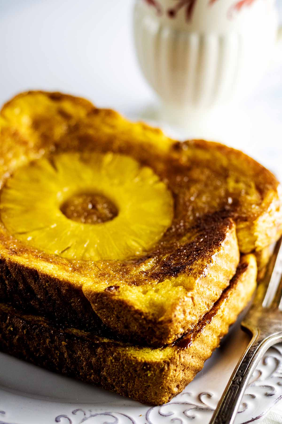 Close up of pineapple French toast sitting on a white plate with a fork
