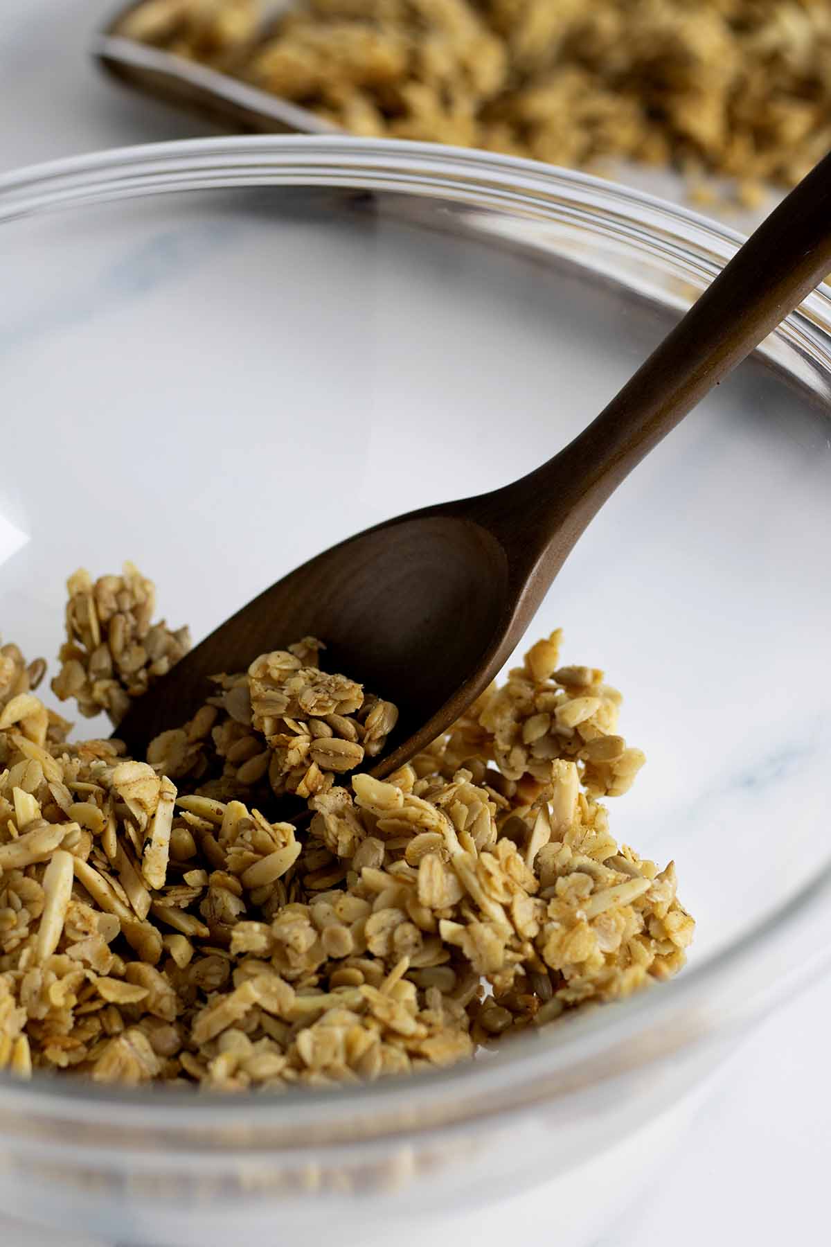 Granola clusters in a glass bowl with a wooden spoon