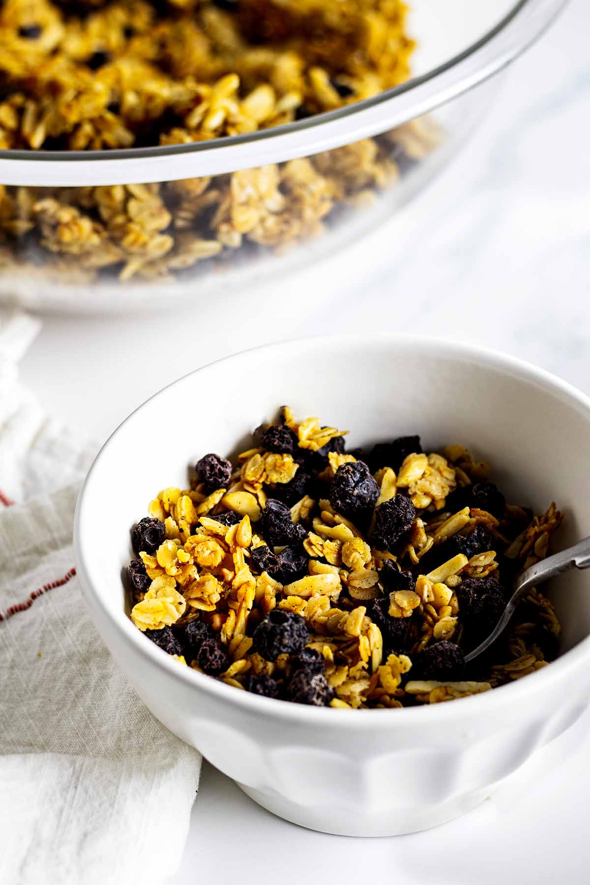 Granola in a white bowl with spoon and white napkin