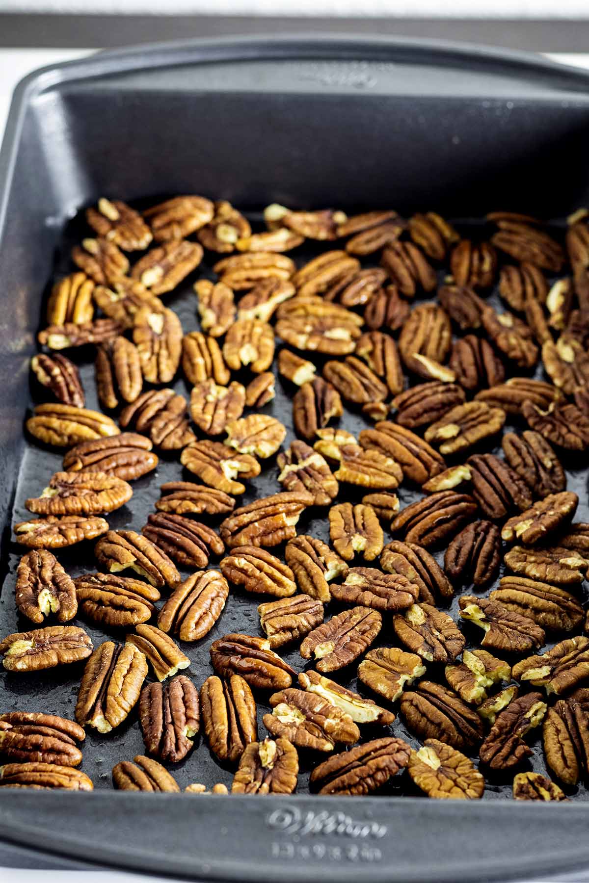 Raw whole pecans in a baking pan.