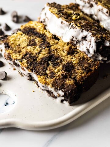 Close up of slices of chocolate chip peanut butter bread on a rectangular white platter with scattered chocolate chips