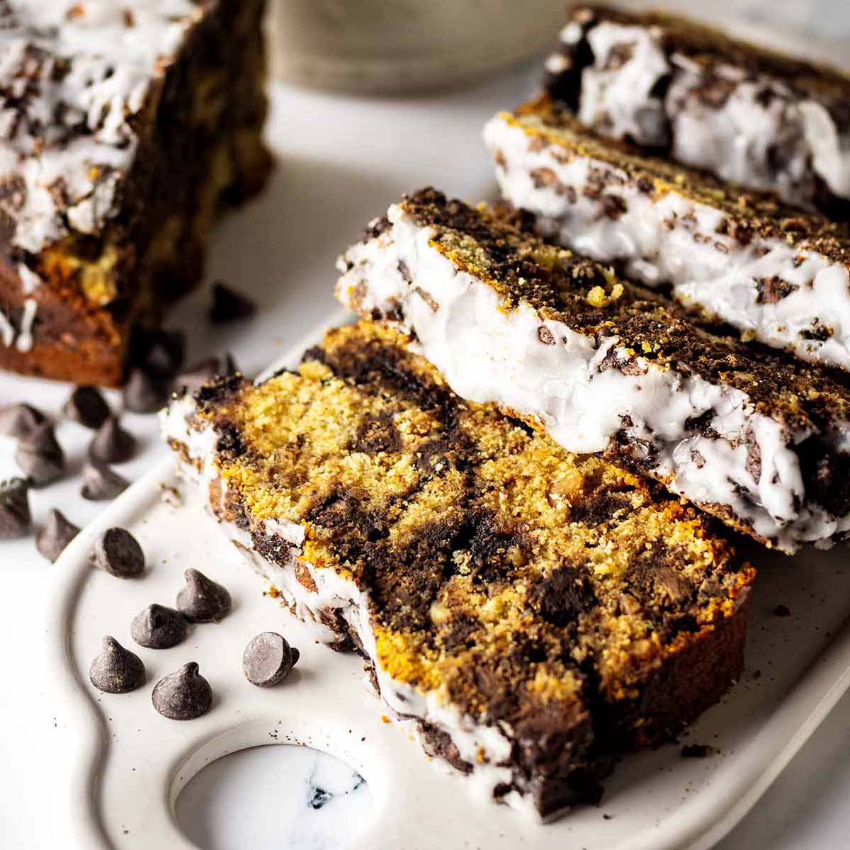 Close up view of Slices of chocolate chip peanut butter bread on a rectangular white platter with scattered chocolate chips