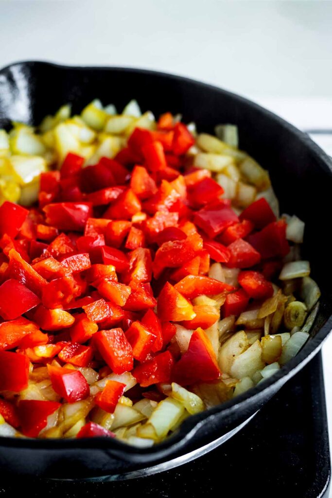 Red bell pepper and onions cooking in a skillet