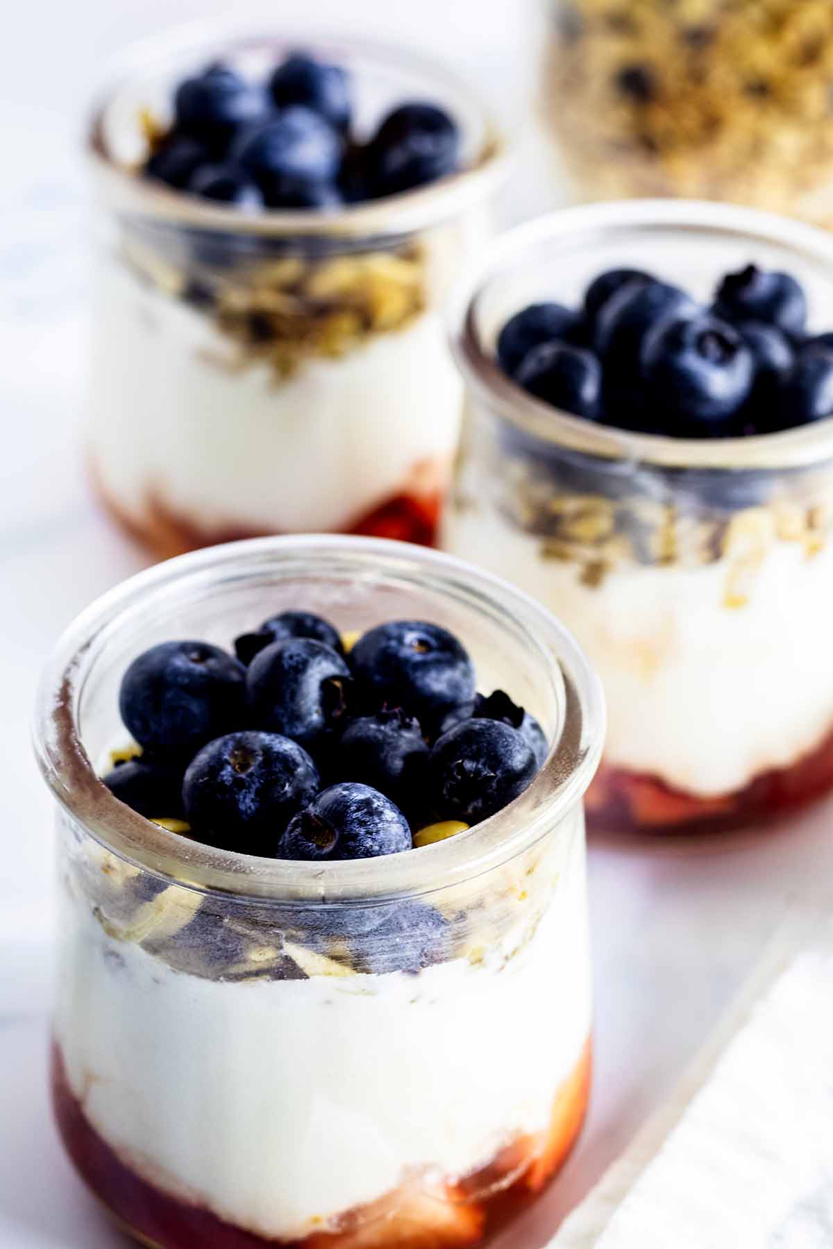 Three berry yogurt parfaits in glass jars