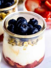 Close up of berry yogurt parfait in a glass jar with sliced strawberries